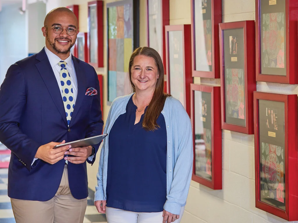 two praxis team members smiling next to a wall of awards