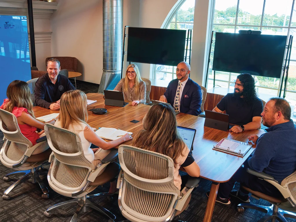 praxis team members in a meeting all smiling sitting around a conference table