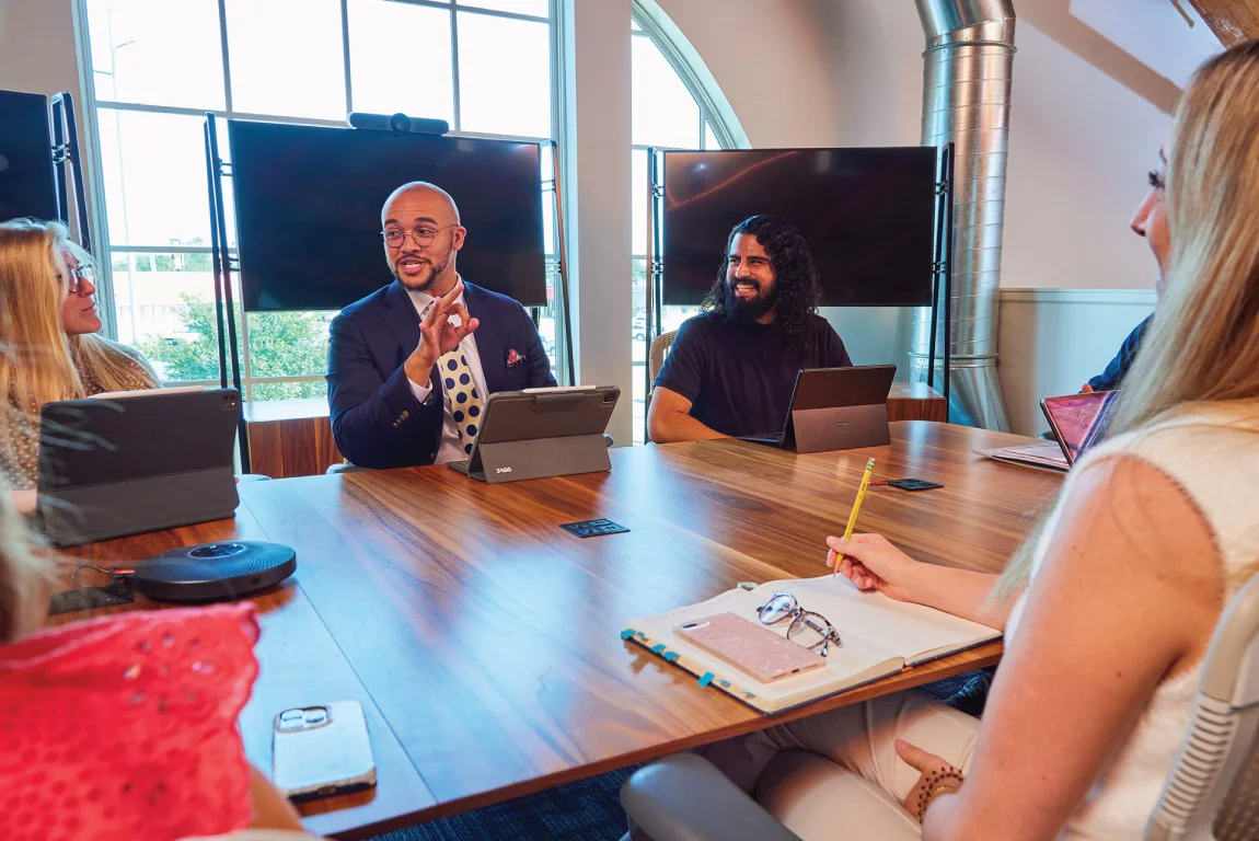 praxis team members in a meeting smiling at conference table male speaker leading discussion