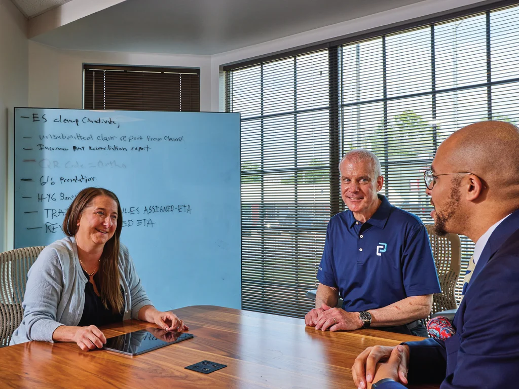 team in discussion at table, white board with ideas behind the table